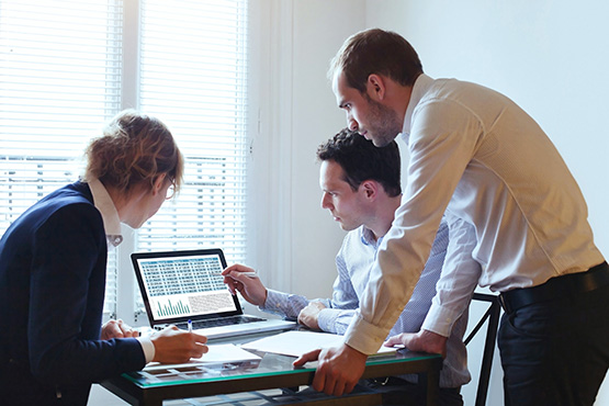 Managers gathered aruond a laptop looking at data